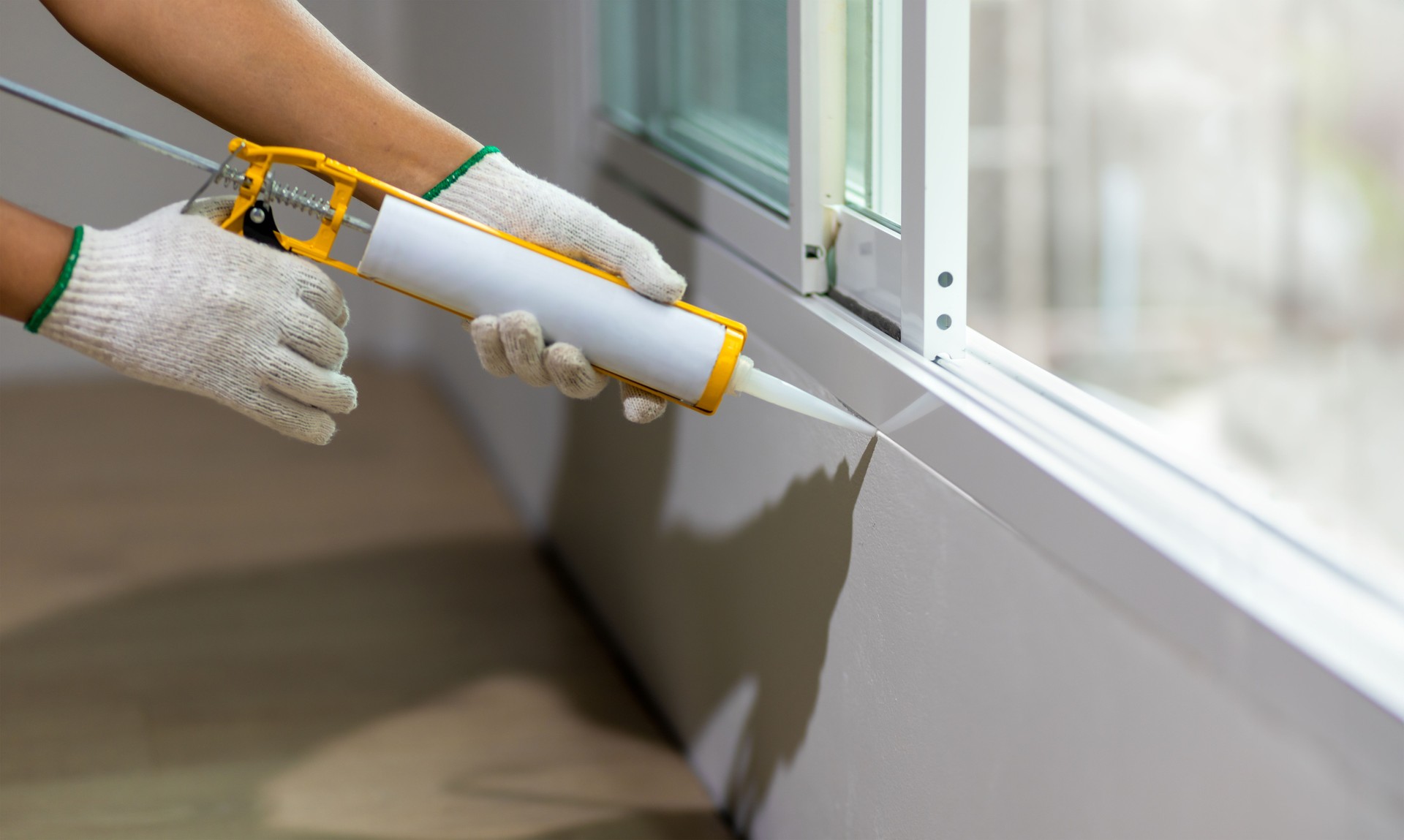 Construction worker using silicone sealant caulk the outside window frame.